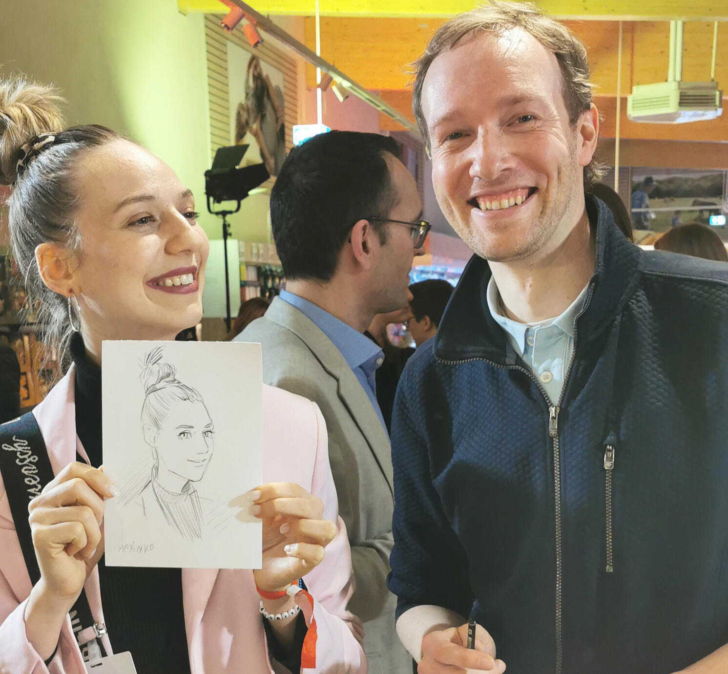 コカ・コーラの企業イベントでのライブ似顔絵。完成したA5サイズの似顔絵を手に、ゲストと笑顔のポートレート。マキシム・シモネンコの実演。